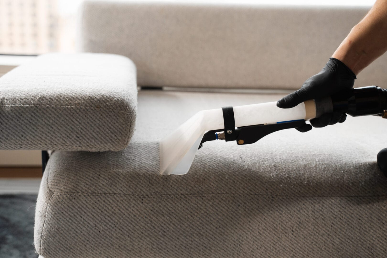 Art of Clean technician deep cleaning upholstery on a fabric sofa