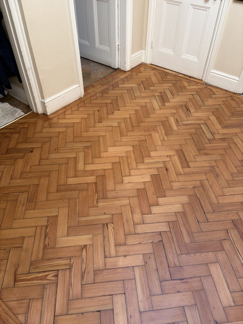 Freshly sanded herringbone wood floor with a rich, even finish